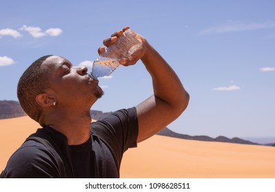 Afro American Man Drinking Water In The Desert