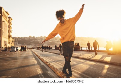 Afro American man having fun walking in city center - Happy young guy enjoying time a sunset outdoor - Millennial generation lifestyle and positive people attitude concept