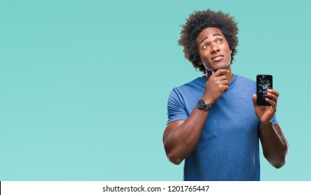 Afro american man holding broken smartphone over isolated background serious face thinking about question, very confused idea