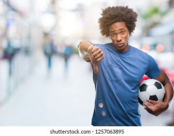 Afro American Man Holding Football Ball Over Isolated Background With Angry Face, Negative Sign Showing Dislike With Thumbs Down, Rejection Concept