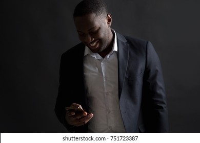 Afro American Man Holding A Mobile Phone While Standing On A Dark Background