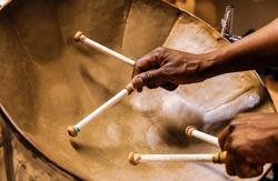 Afro American Man Plays The Steel Drum Using Two Hands And Four Drumsticks