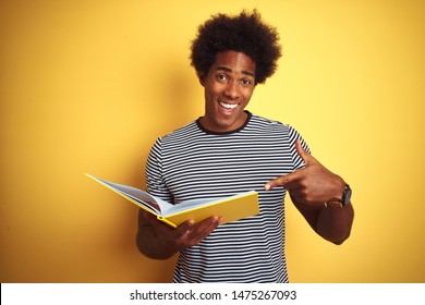 Afro American Student Man Reading Book Standing Over Isolated Yellow Background Very Happy Pointing With Hand And Finger