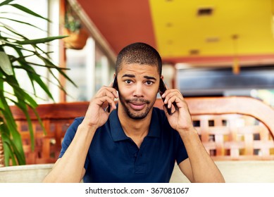 Afro American Talking On Two Smart Phones And Looking At Camera.