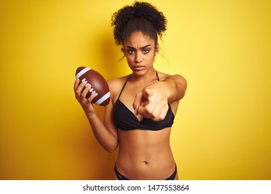 Afro american woman on vacation wearing bikini playing rugby over isolated yellow background pointing with finger to the camera and to you, hand sign, positive and confident gesture from the front - Powered by Shutterstock