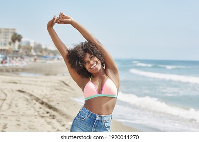 Afro-Amerikanerin, die sich die Hände über Kopf auf Strand lacht