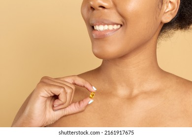 Afro American Woman Taking Beauty Supplements For Glowing Skin. Black Smiling Woman Holding Vitamin C In Her Hand.