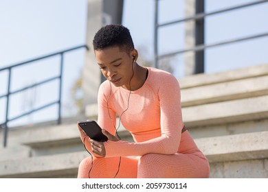 Afro American Woman Tired After Workout Listening To Music And Audio Podcast, After Jogging And Training At Stadium In Morning