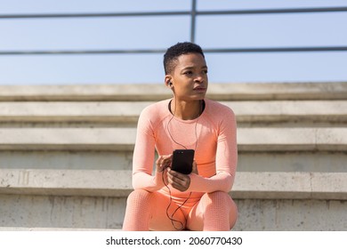 Afro American Woman Tired After Workout Listening To Music And Audio Podcast, After Jogging And Training At Stadium In Morning