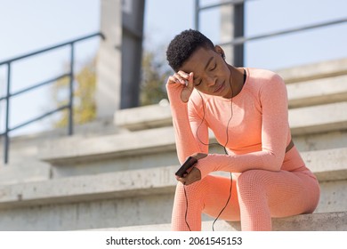 Afro American Woman Tired After Workout Listening To Music And Audio Podcast, After Jogging And Training At Stadium In Morning