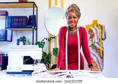 afro american woman with turban over head and silver ethnic colorful jewelry in tailor workshop