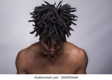 An Afro American Young Fit Athletic Shirtless Man With Afro Hair With The Head Down, Isolated On Grey Background