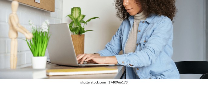 Afro American Young Woman Student Freelancer Distance Worker Using Laptop Elearning Online Course Work Study From Home Office Typing On Computer At Desk. Horizontal Photo Banner For Website Design.