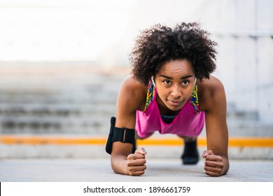 Afro athlete woman doing pushups outdoors.