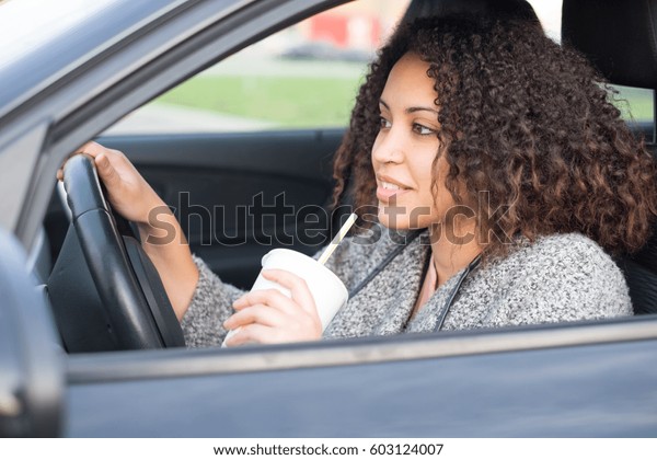 Afro black woman\
drinking and driving her\
car