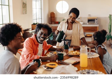 Afro Brazilian family happily gathers for a breakfast filled with pão de queijo and drip coffee. Mother serving her family a traditional breakfast with smiles, love, and togetherness at home. - Powered by Shutterstock