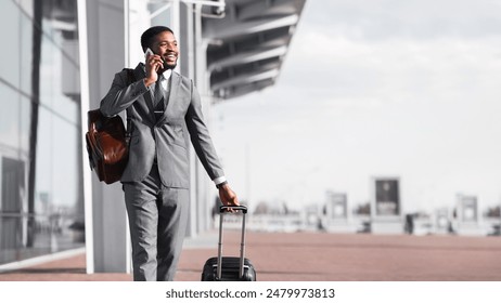 Afro Businessman Walking With Luggage And Talking On Phone, Arriving To Airport - Powered by Shutterstock