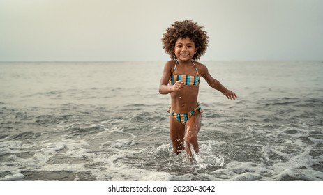 Afro child having fun playing inside sea water during summer holidays - Childhood and travel vacation concept - Powered by Shutterstock