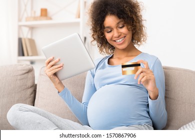 Afro expectant woman doing online shopping and paying by credit card on sofa - Shutterstock ID 1570867906