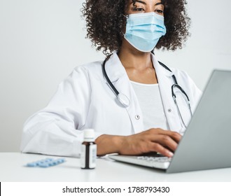 afro female doctor with surgical mask in her office using a laptop - Powered by Shutterstock