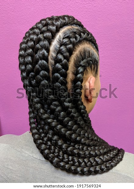 Afro Hair Braided In A
Cornrow Hairstyle Using Black Synthetic Hair Extensions, Purple
Background 