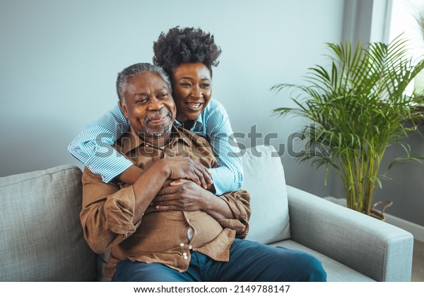 Afro hispanic-latino father and daughter together at\
home. Family is everything - Family Tie. Adult Daughter Hugging\
Senior Man. Senior black man and his middle aged daughter\
embracing, close up