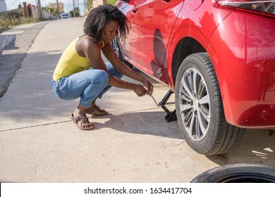 Afro Woman Changing A Flat Tire On Her Red Car