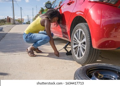 Afro Woman Changing A Flat Tire On Her Red Car