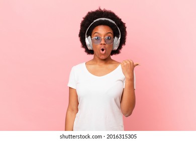 afro woman looking astonished in disbelief, pointing at object on the side and saying wow, unbelievable. music concept