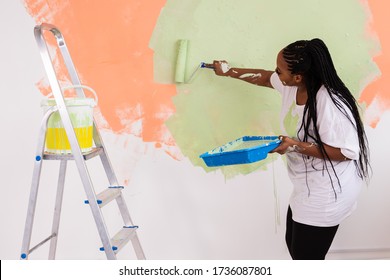Afro Woman Painting The Walls Of New Home. Renovation, Repair And Redecoration Concept.