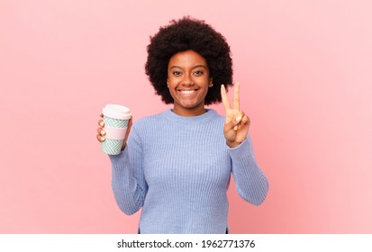 Afro Woman Smiling And Looking Friendly, Showing Number Two Or Second With Hand Forward, Counting Down. Coffee Concept