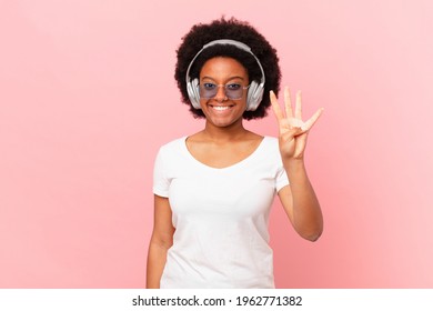 Afro Woman Smiling And Looking Friendly, Showing Number Four Or Fourth With Hand Forward, Counting Down. Music Concept