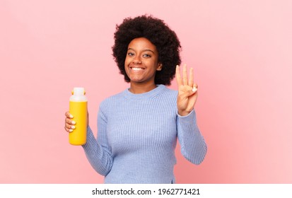 Afro Woman Smiling And Looking Friendly, Showing Number Three Or Third With Hand Forward, Counting Down. Smoothy Concept