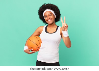 Afro Woman Smiling And Looking Friendly, Showing Number Two Or Second With Hand Forward, Counting Down. Basketball Concept