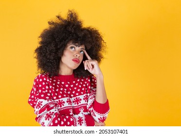 Afro woman wearing christmas clothes, thinking, yellow background - Powered by Shutterstock