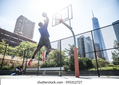 Afroamerican athlete playing basketball outdoors - Basketball player dunking on court in New York - Powered by Shutterstock