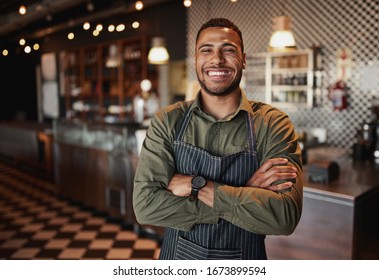 Afro-american cafe owner standing smiling wearing apron with folded arms
