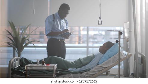 Afro-american Detective Interrogating Woman Victim Lying In Hospital Bed. Side View Of Black Female Patient Resting In Bed And Talking To Police Officer In Hospital Ward