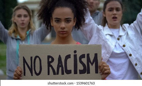 Afroamerican girl holding No racism sign, activists chanting Human rights slogan