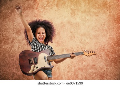 Afro-American little girl playing guitar on grunge background