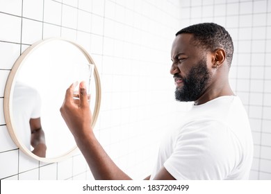 Afro-american Man Grimacing From Bad Taste Of Water And Holding Glass In Hand