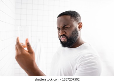 Afro-american Man Grimacing From Bad Taste Of Water And Holding Glass In Hand