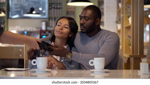 Afro-american Man Paying Bill With Smartphone At Restaurant. African Couple On Date Paying With Contactless Cellphone App In Cafe