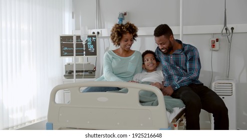 Afro-american Parents Visit Sick Son At Hospital Ward. Young Mother And Father Hugging And Supporting Ill Son Lying In Bed At Hospital. Healthcare And Family Concept