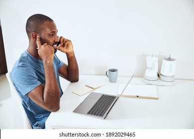 Afro-American Person In A White Room Shutting His Ear With A Finger While Talking On The Phone
