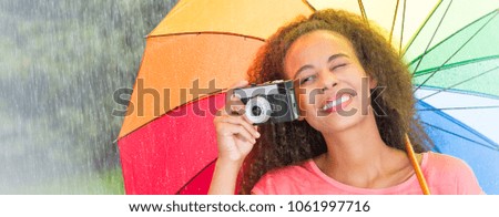 Afroamerican woman taking a picture with analog camera under umbrella