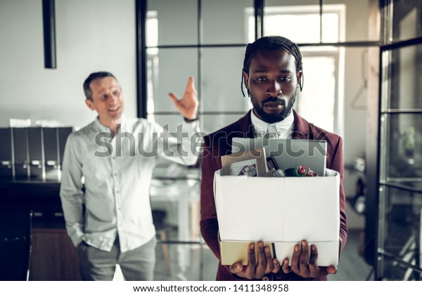 After being fired. Bearded\
dark-skinned trainee feeling awful after being fired by his angry\
boss