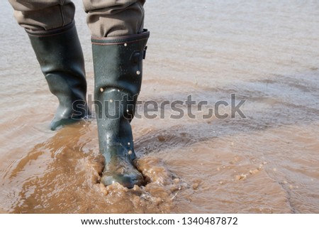 After the big rain it goes with rubber boots through a rain puddle in the meadow.
