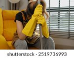 after cleaning house all day she feel tired and sit on the sofa on the floor, she have done a lot of housework since morning until noon that is made she need some rest, cleaning apartment, remove dust