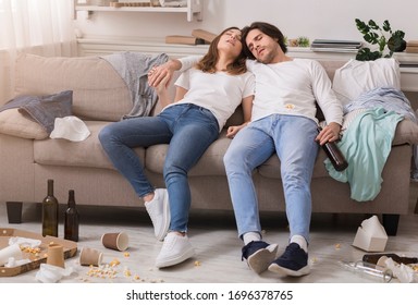 After Party. Drunk Millennial Couple Sleeping Tegether On Couch In Messy Room With Empty Beer Bottles And Box From Pizza Around